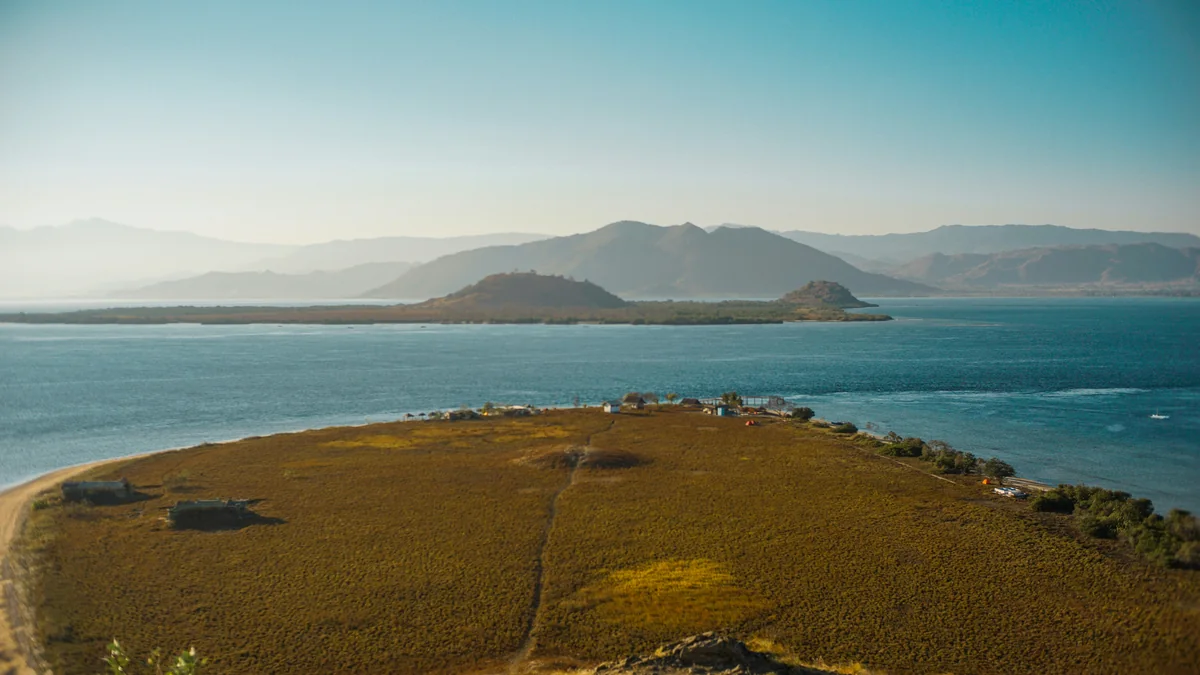 Dry grassy headland beside blue water, with islands and distant hills in Sumbawa